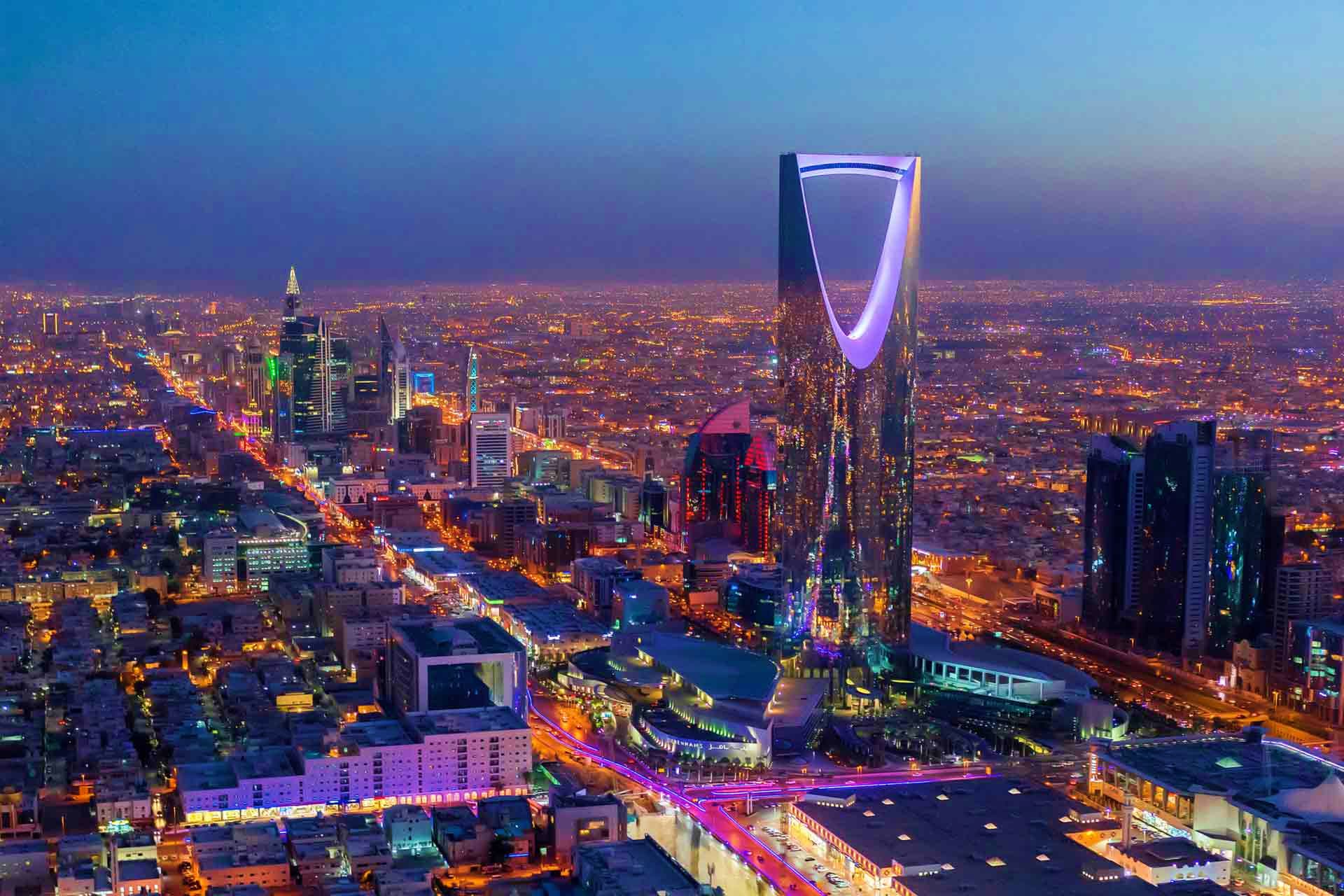 Riyadh skyline at night showing illuminated Kingdom Centre tower and city buildings with traffic on streets below